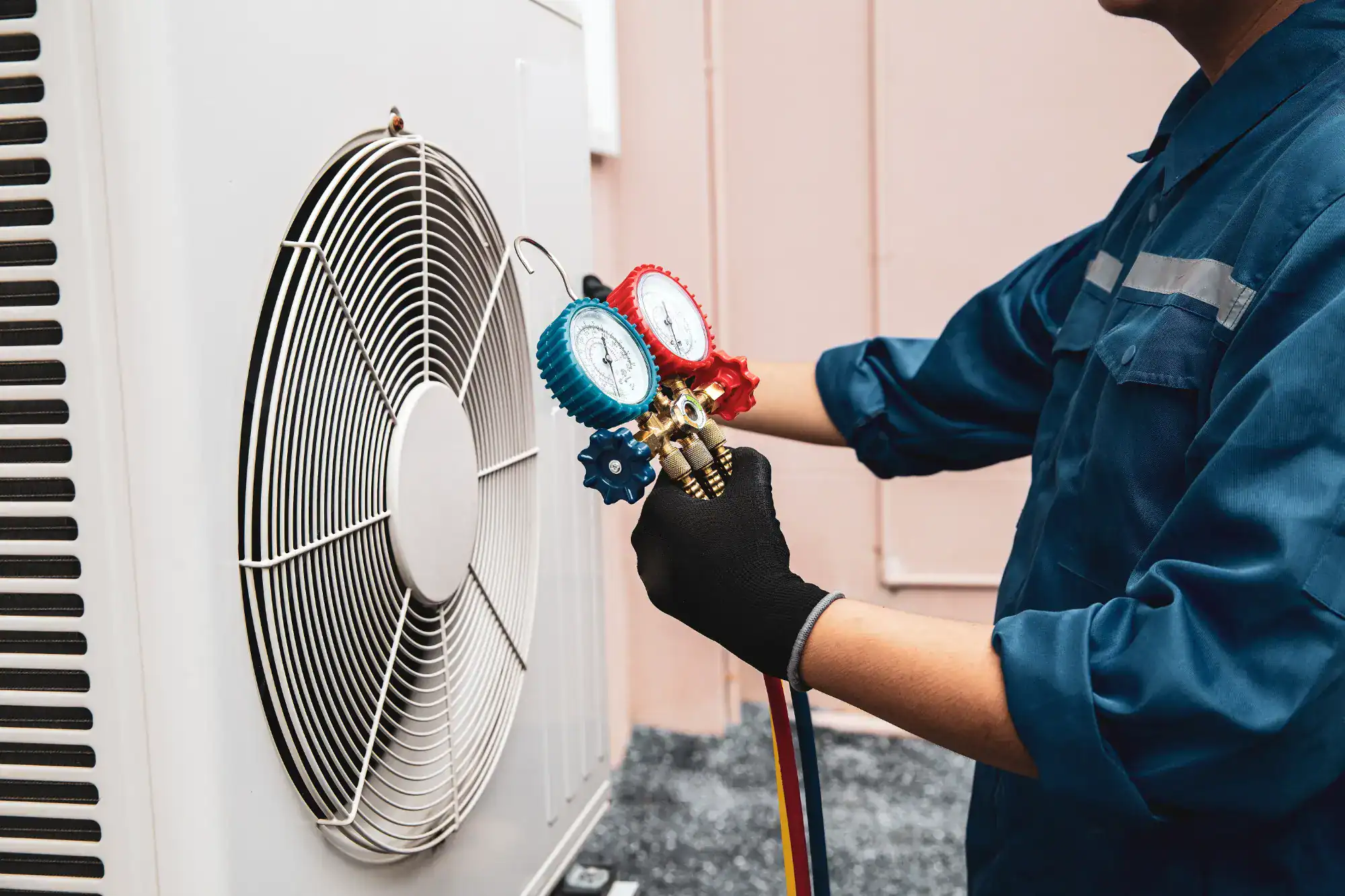 A man in blue shirt fixing an air conditioner.