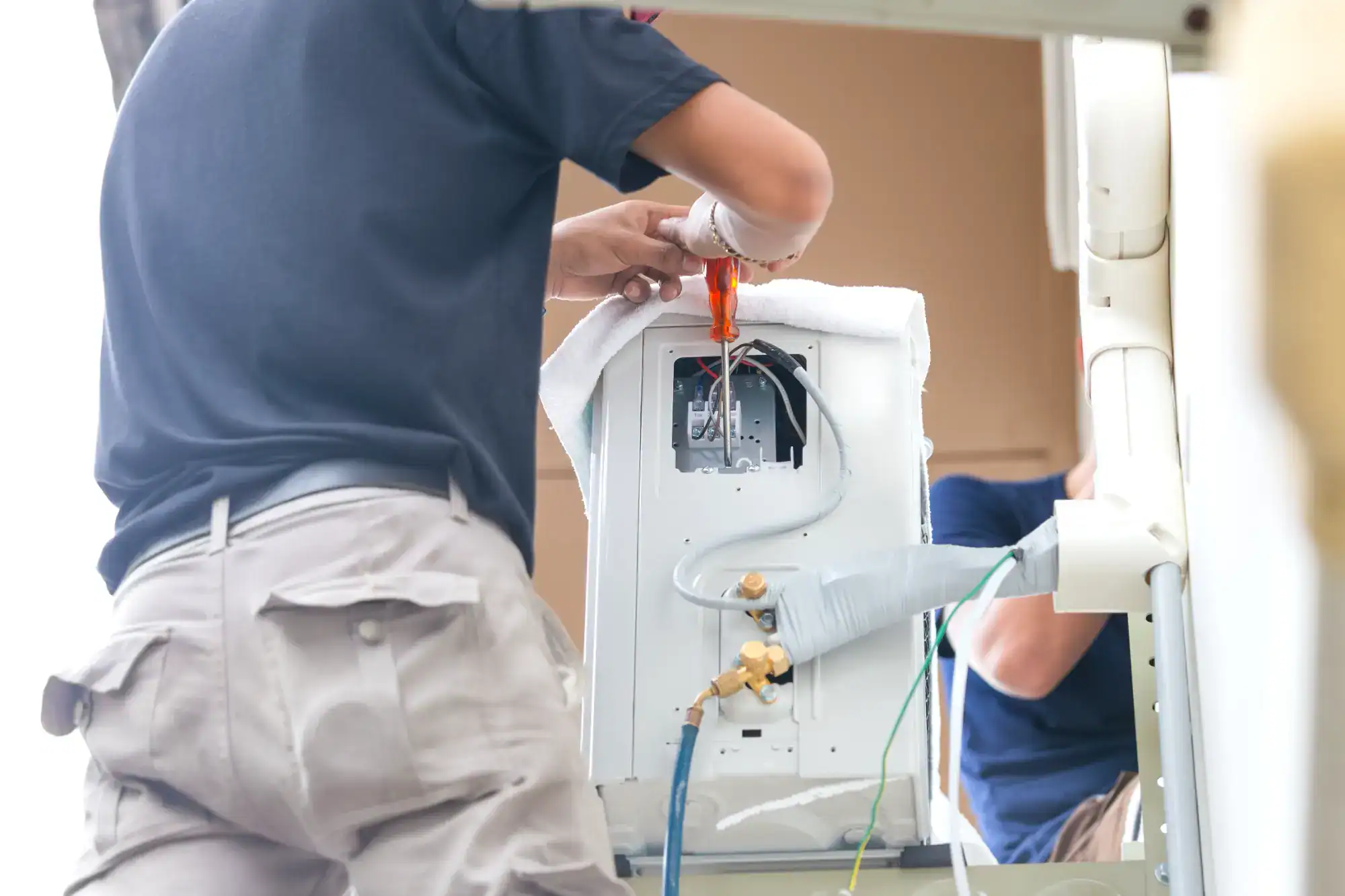 Two men working on a refrigerator in a warehouse.