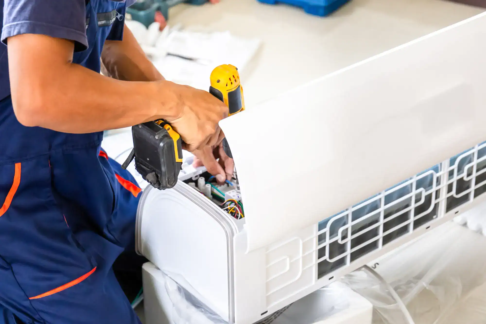 A man is working on a refrigerator in a room.