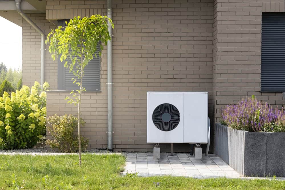A heat pump is outside of a house.